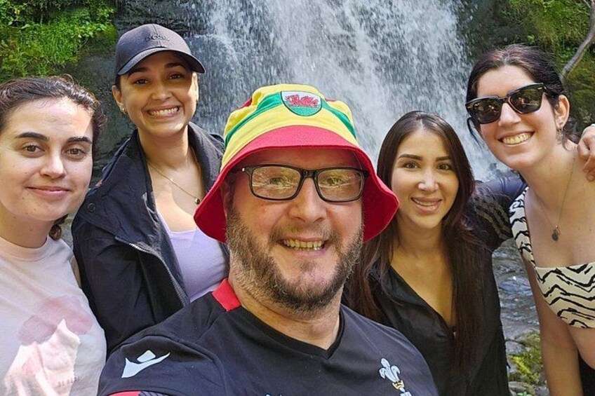 A group of people standing in front of a waterfall. 5