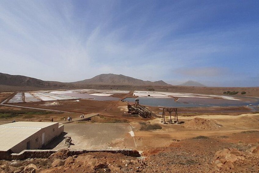 A dry, arid landscape with a large water body, a concrete structure, and distant mountains. 3