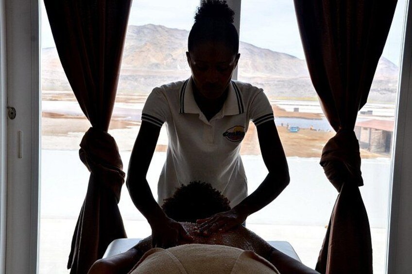 A person receiving a massage in a room with a window view of a desert landscape. 1