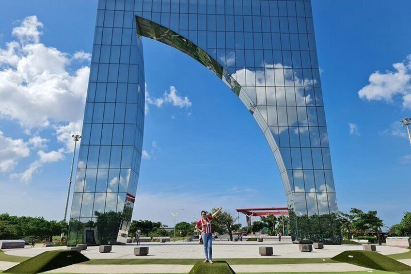 A modern glass building with a curved structure, a clear blue sky, and a person standing in front. 5