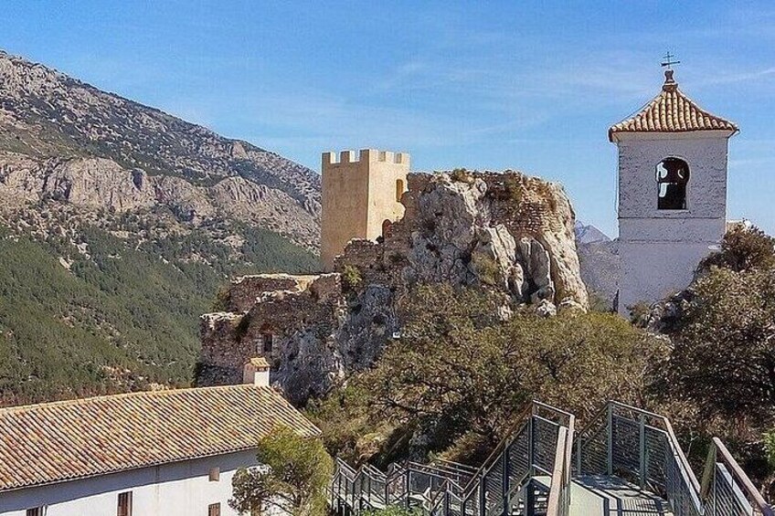 Une tour de pierre historique, un bâtiment fortifié et un escalier menant au sommet d’une colline. 1