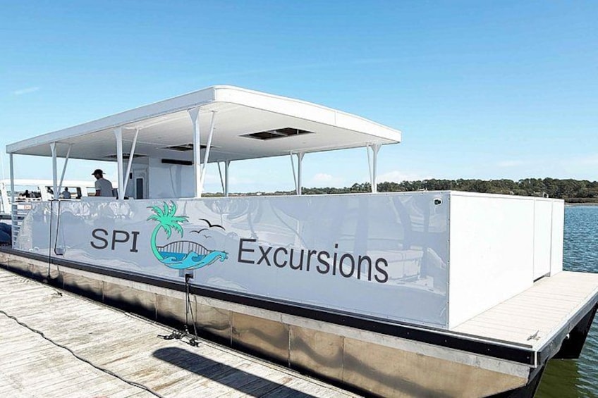 A boat docked at a pier with a white structure on top, labeled 'SPI Excursions.' 2