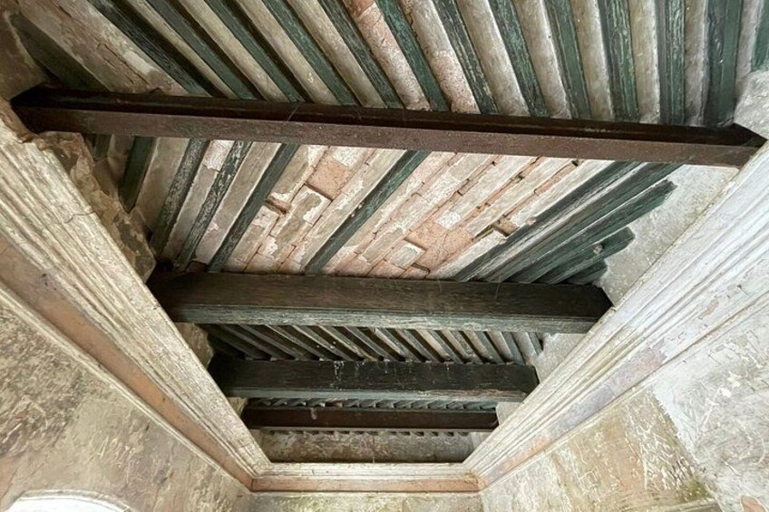 A ceiling with wooden beams and a metal bar. 4