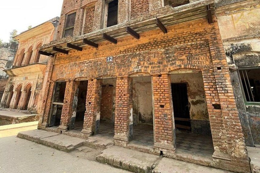 A dilapidated brick building with arched doorways and numbered windows. 5