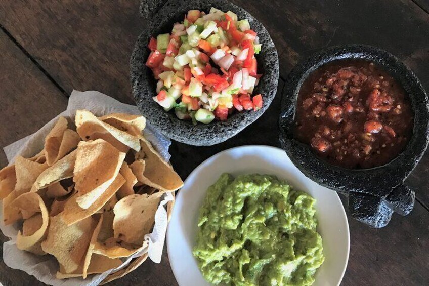 Tortilla chips, guacamole, salsa, and pico de gallo on a wooden table. 5