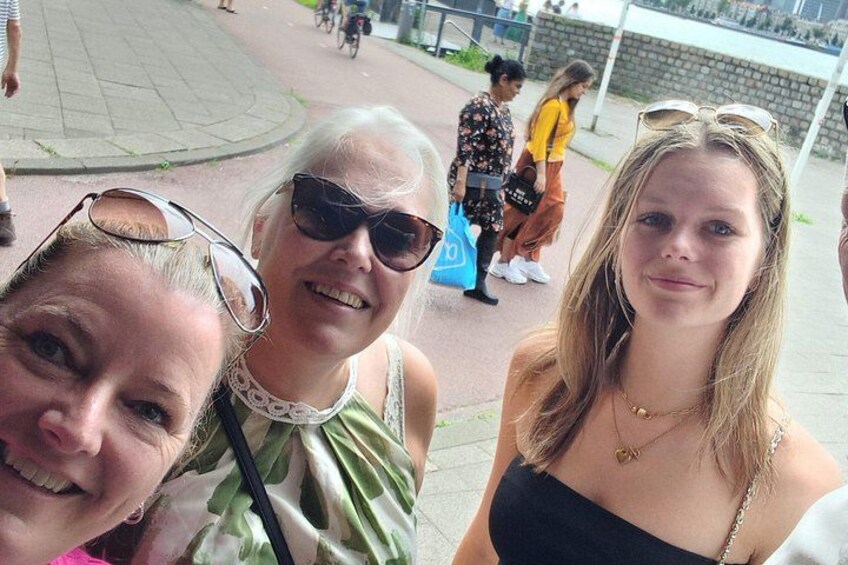 Three people taking a selfie in a public square with a circular walkway and a stone wall in the background. 2