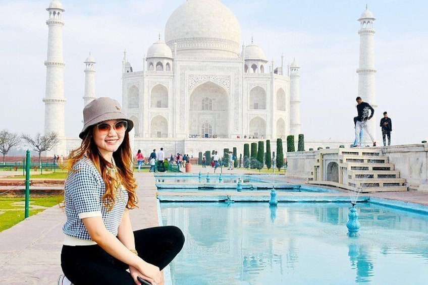 Iemand zit bij een zwembad, met de Taj Mahal op de achtergrond. 3