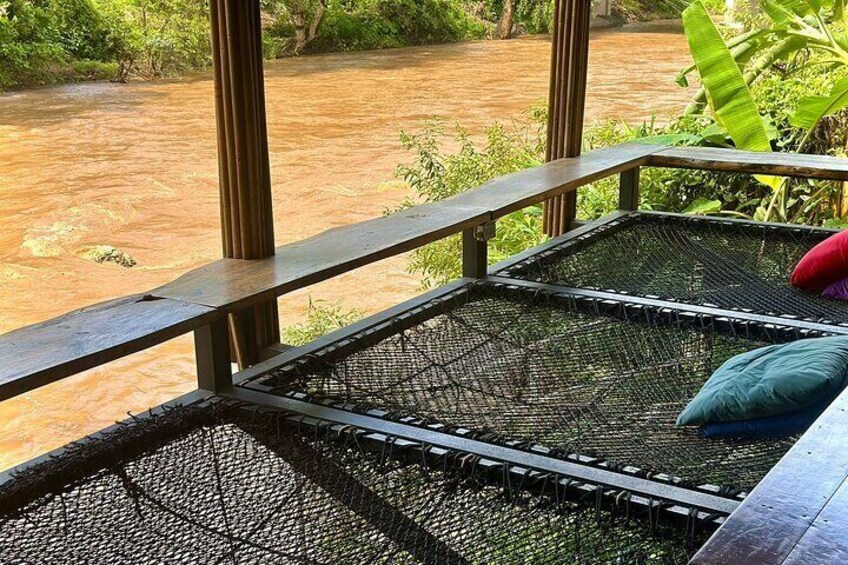 A riverside view from a balcony with a mesh floor, surrounded by greenery. 1