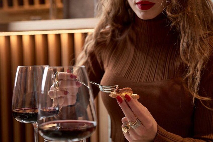 A person holding a wine glass and a fork with a piece of food. 2