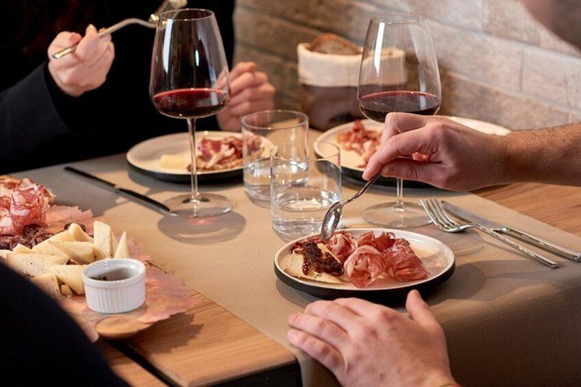 A dining table with plates of food, glasses of red wine, and cutlery. 5