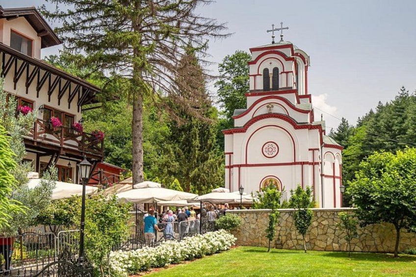 Eine Kirche mit einem Glockenturm, umgeben von einem Garten mit weißen Blumen und einer Steinmauer. 2