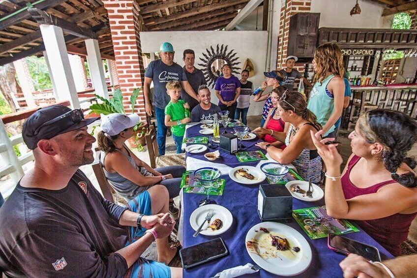 A group of people dining at an outdoor restaurant with brick walls and a sunburst decoration. 2