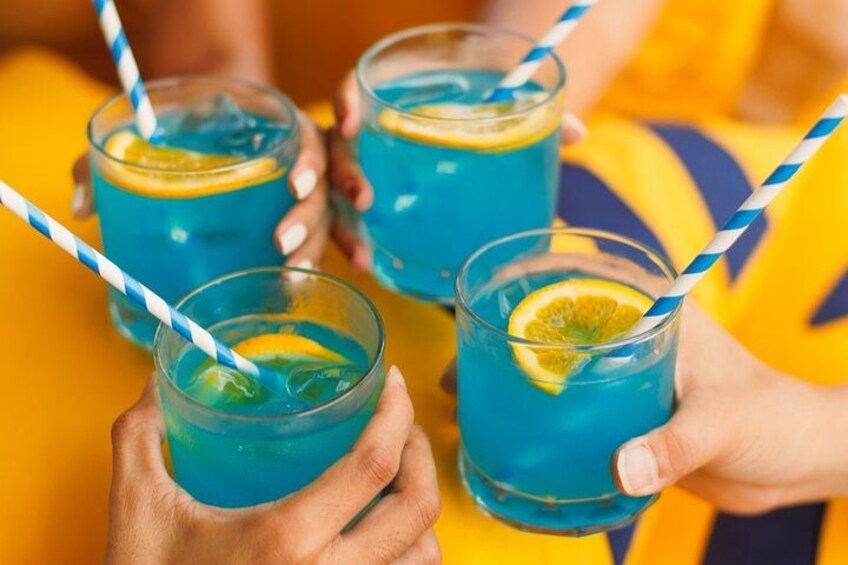 Three glasses of blue beverage with lemon slices and striped straws. 2