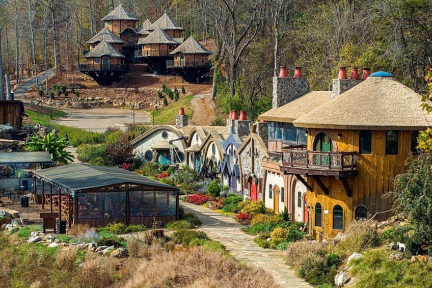 A fantasy-themed resort with unique treehouse structures, a pathway, and lush landscaping. 1