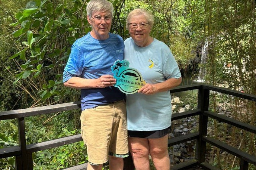 Twee personen staan op een houten brug, met groen in de achtergrond. 4
