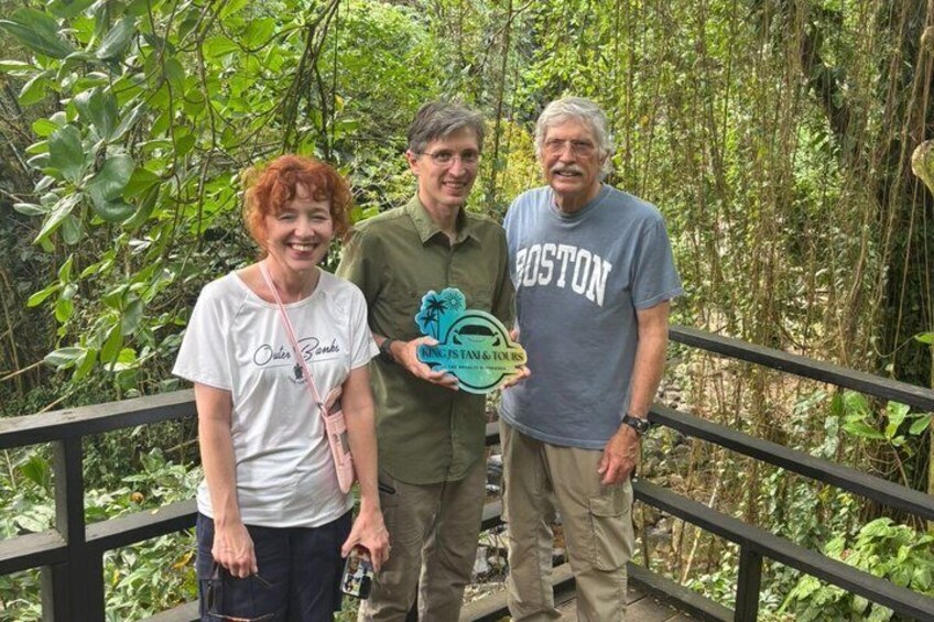Tres personas de pie sobre un puente de madera rodeado de abundante vegetación. 3