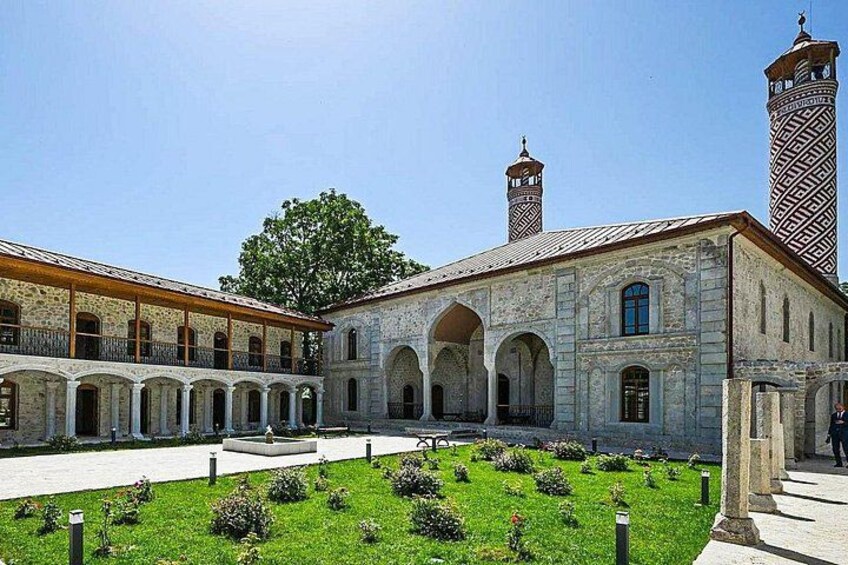 Un patio con un edificio que cuenta con ventanas de arco y un minarete. 5