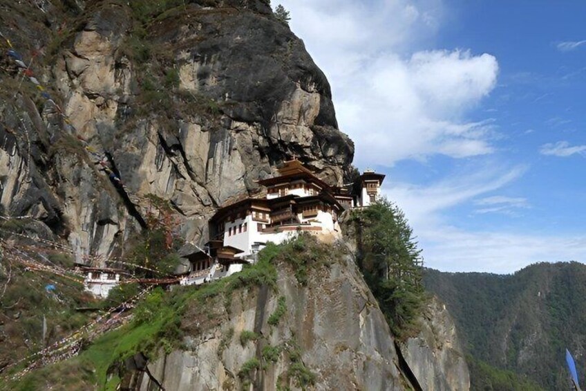 A monastery perched on a cliffside with a mountainous backdrop. 3