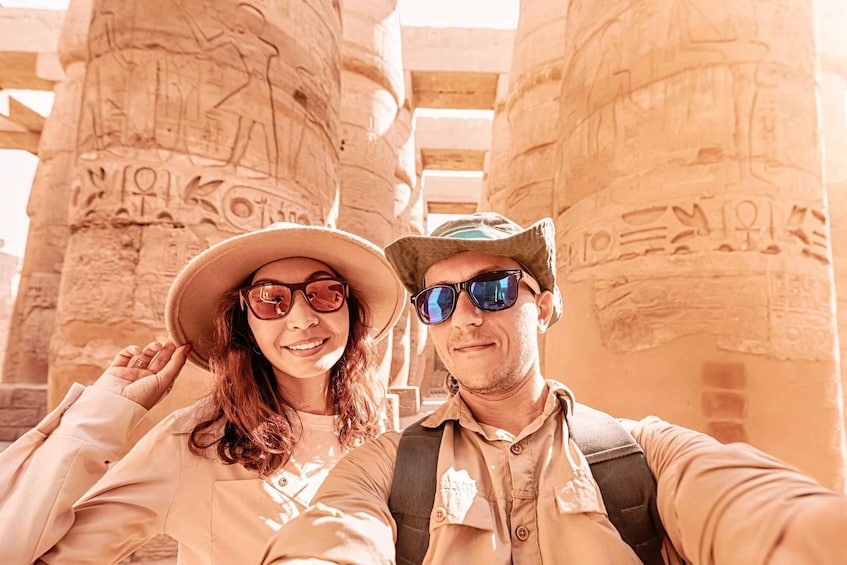A couple taking a selfie with ancient Egyptian hieroglyphs in the background. 3