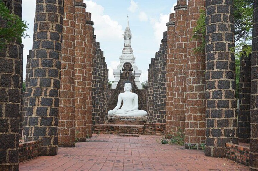 A white statue of a seated figure in a temple courtyard, surrounded by brick walls. 3