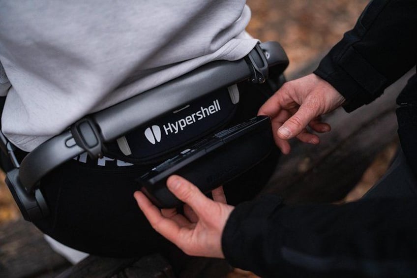 A person adjusting a black Hypershell backpack. 2