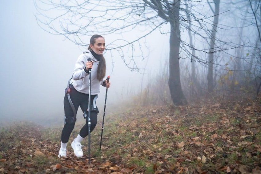 A person hiking in a foggy forest with bare trees and fallen leaves on the ground. 3