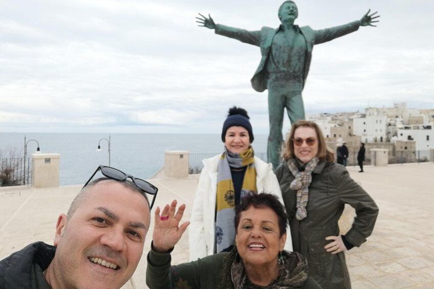 Eine Gruppe von Personen posiert vor einer Statue und einer Küstenstadt. 2