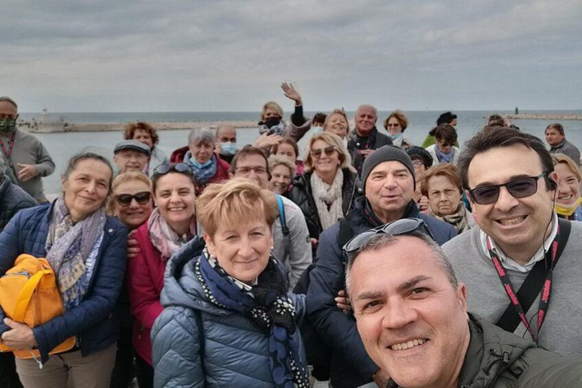 Eine Gruppe von Menschen an der Küste, im Hintergrund ein Steg. 4