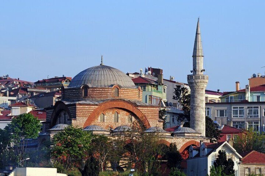 Eine Moschee mit einer großen Kuppel und einem Minarett, umgeben von Wohnhäusern. 4