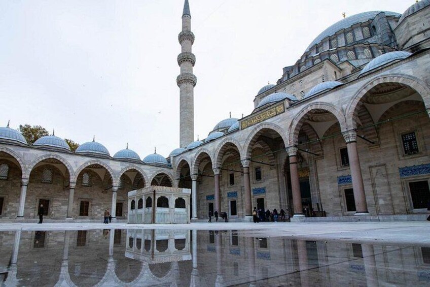 A mosque with a tall minaret, arched walkways, and a reflective courtyard. 5