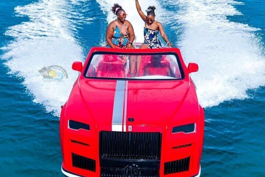 Une voiture rouge décapotable avec deux personnes à bord, qui roule sur l’eau. 3