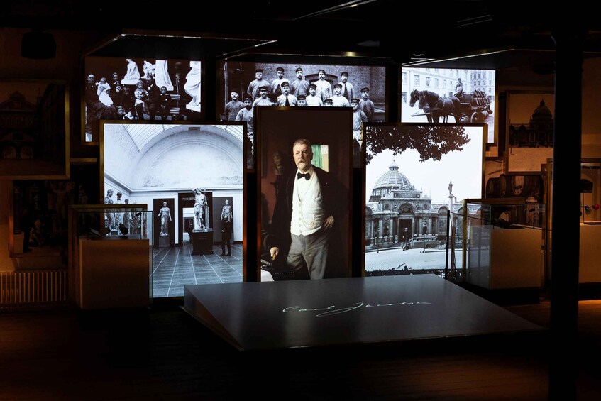 A museum exhibit with historical photographs and a central portrait. 2