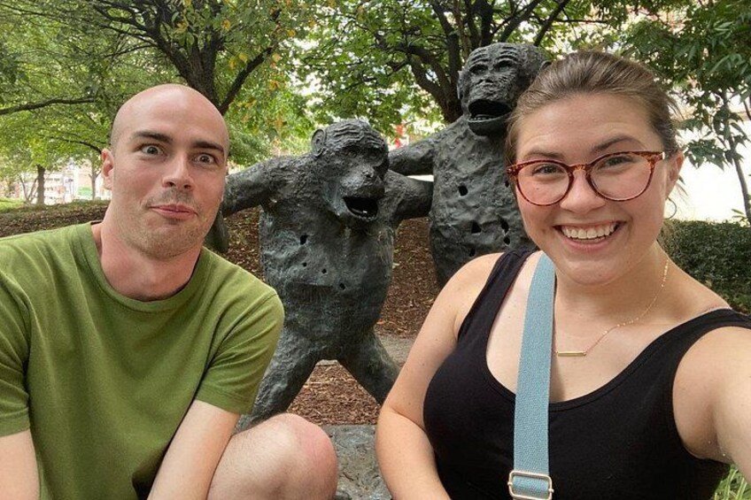 Two people sitting in front of a sculpture of a dog. 3