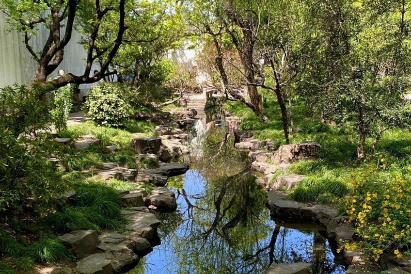 A serene garden with a pond, rocks, and lush greenery. 3