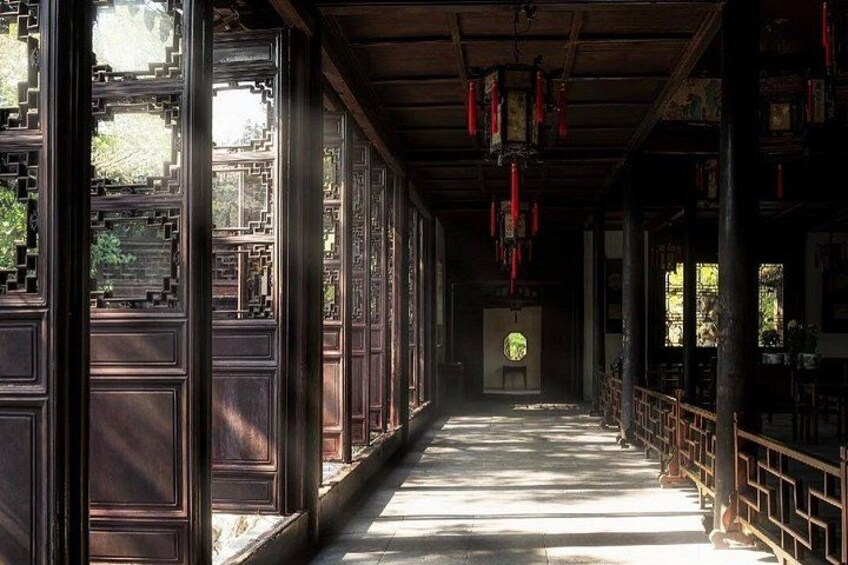 A traditional corridor with wooden doors and windows, red lanterns, and a tiled floor. 2