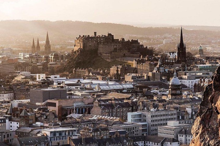 A cityscape with a prominent castle on a hill, surrounded by historic buildings and modern structures. 3