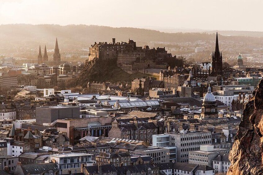 A cityscape with a prominent castle on a hill, surrounded by historic buildings and modern structures. 2