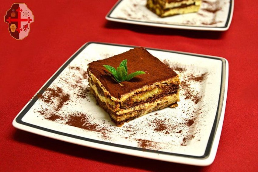 En bit av en dessert med flera lager, serverad på en vit tallrik med en röd bakgrund. 4