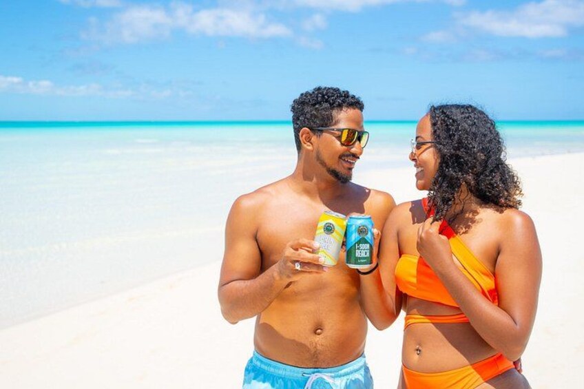 Two people on a beach holding drinks. 3