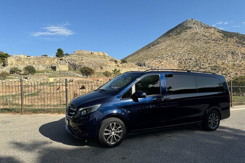 En mørkeblå minivan parkeret på en vej med et bjergrigt baggrundsmotiv. 3