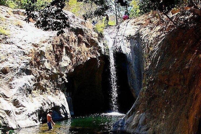Una cascata che si getta in una pozza circondata da terreno roccioso. 1