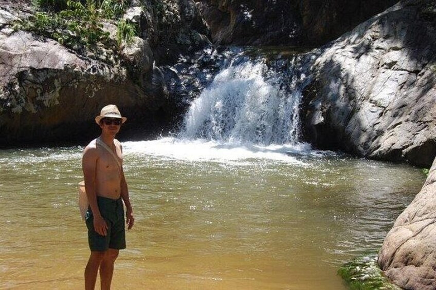 Una persona in piedi in acque basse con una cascata sullo sfondo. 3