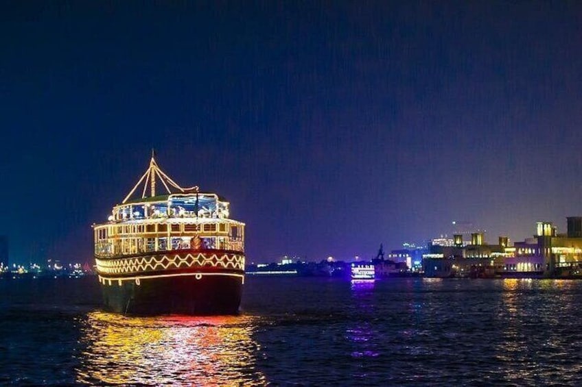 A brightly lit boat with a traditional design on a body of water at night. 1