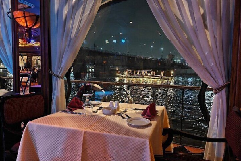 A table set for dining with a view of a waterfront at night. 3