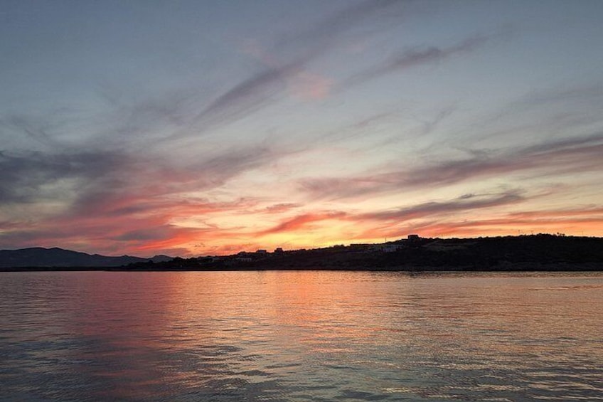 A sunset over a calm body of water with a distant shoreline. 2