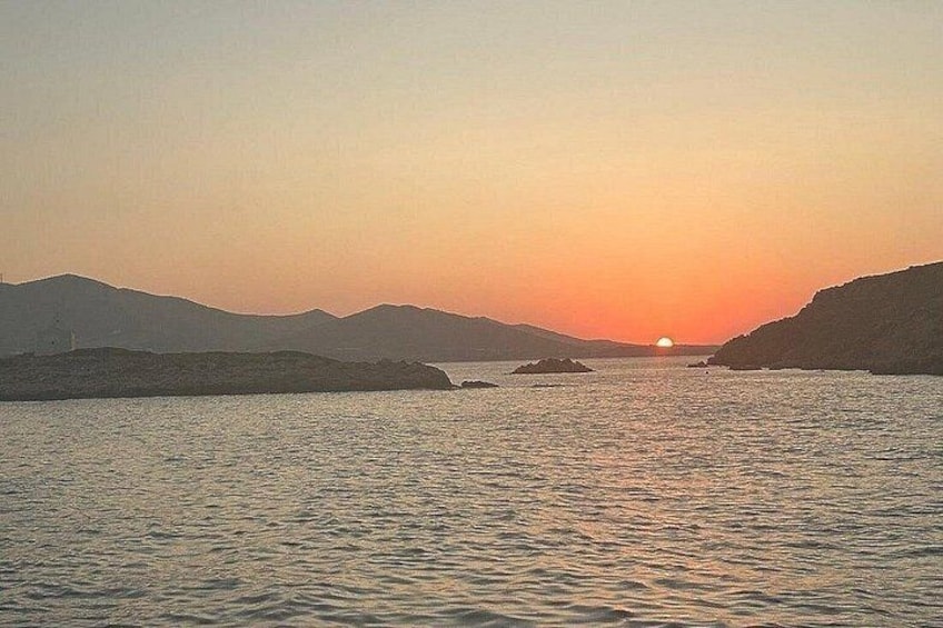 A sunset over a calm sea with distant landforms. 4