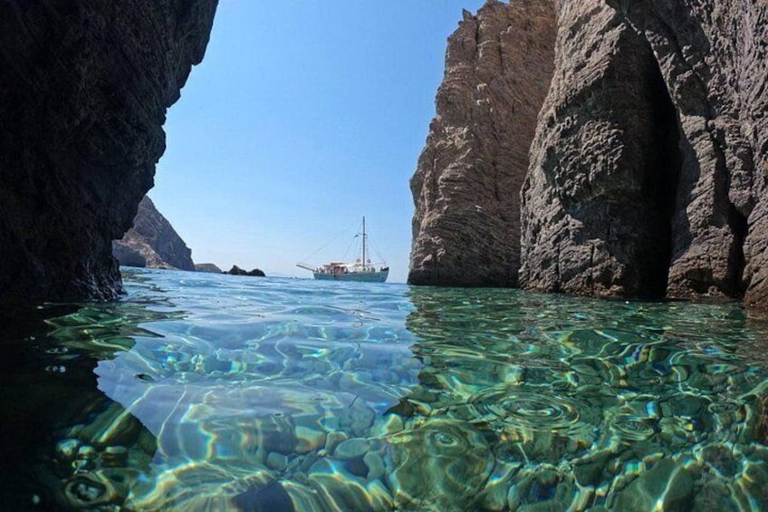 A clear blue sea, rocky cliffs, and a boat in the distance. 3