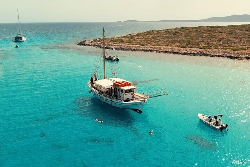 A boat anchored in turquoise waters with a rocky island in the background. 1