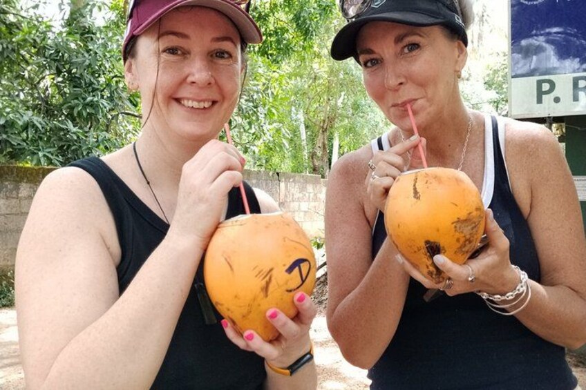 To personer holder orange kokosnødder med sugerør. 2