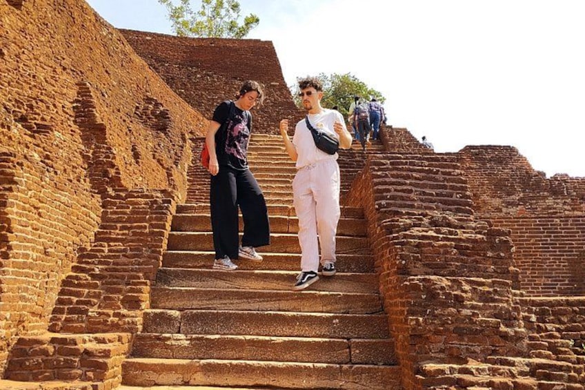 A person standing on a brick staircase with another person in the background. 2